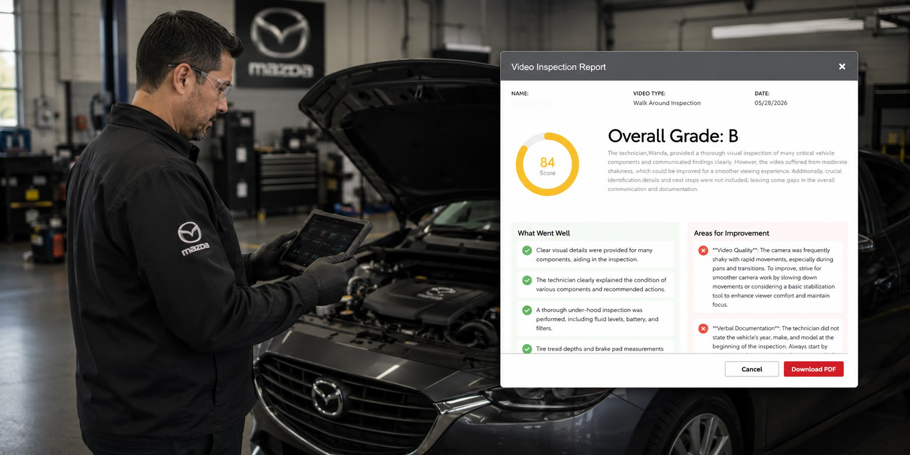 Mechanic in black Mazda uniform using a tablet to inspect a car in a service bay with a large video inspection report on screen.