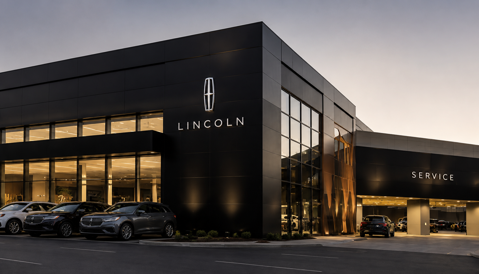 Modern Lincoln dealership exterior at dusk with a dark glass facade, logo, illuminated showroom windows, and several SUVs parked along the curb (SERVICE entrance to the right).